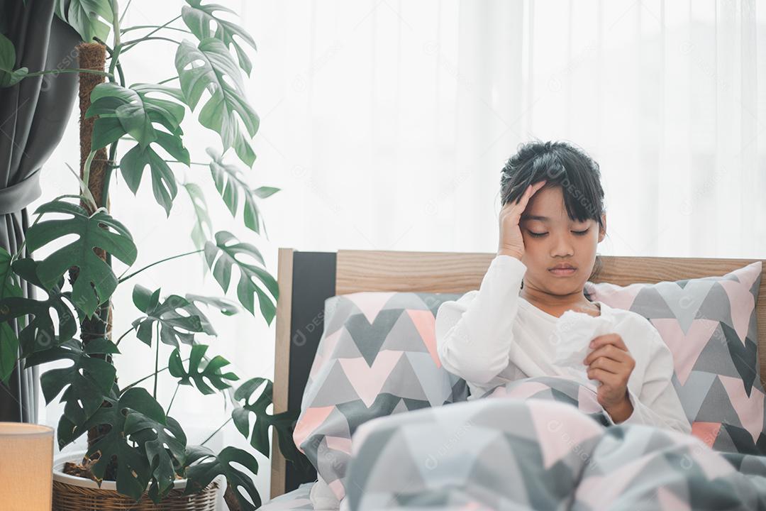 Uma garotinha está gripada, fica em casa debaixo de um cobertor, sua cabeça dói