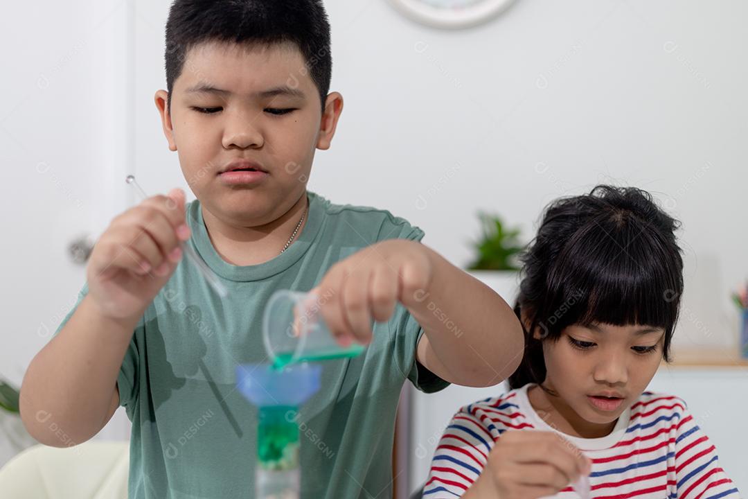 Crianças asiáticas assistem com entusiasmo aos experimentos de química.