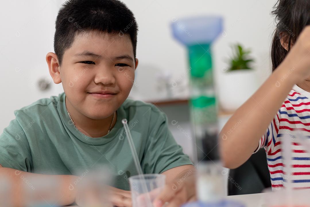 Crianças asiáticas assistem com entusiasmo aos experimentos de química.