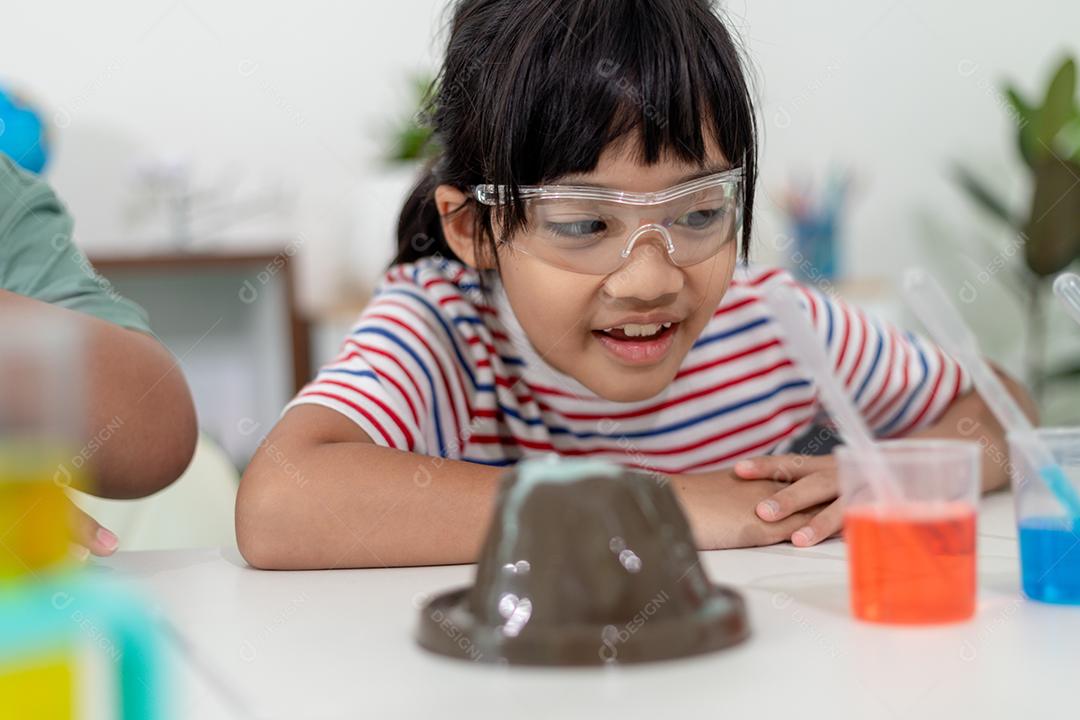 Crianças asiáticas assistem com entusiasmo aos experimentos de química.