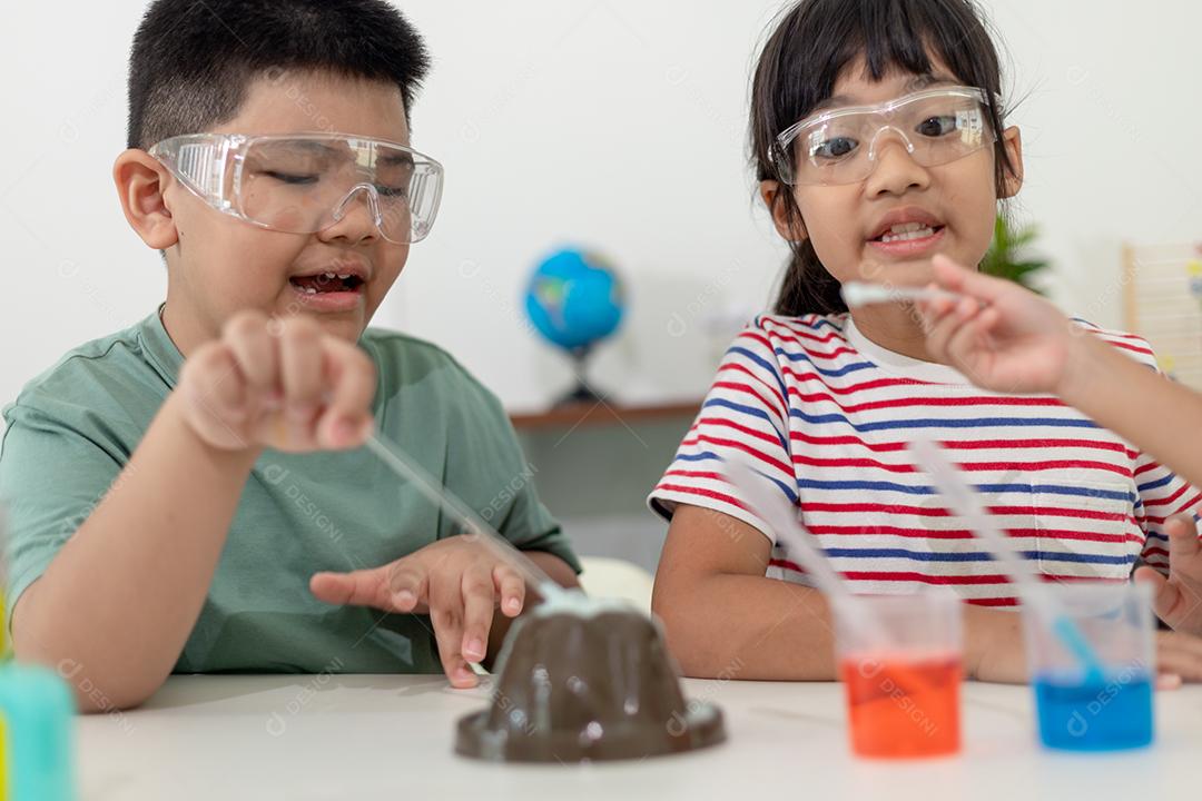 Crianças asiáticas assistem com entusiasmo aos experimentos de química.