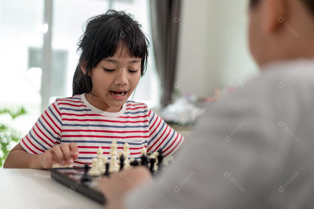 Menino e menina estão jogando xadrez em casa. Crianças jogando xadrez
