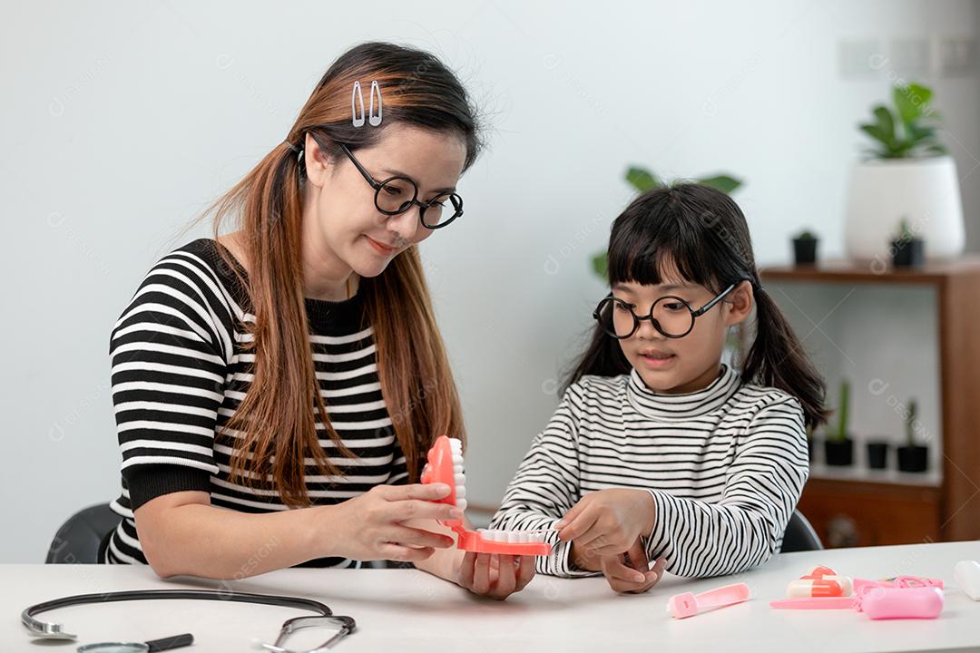 Mãe ensina sua filha criança a escovar os dentes com precisão