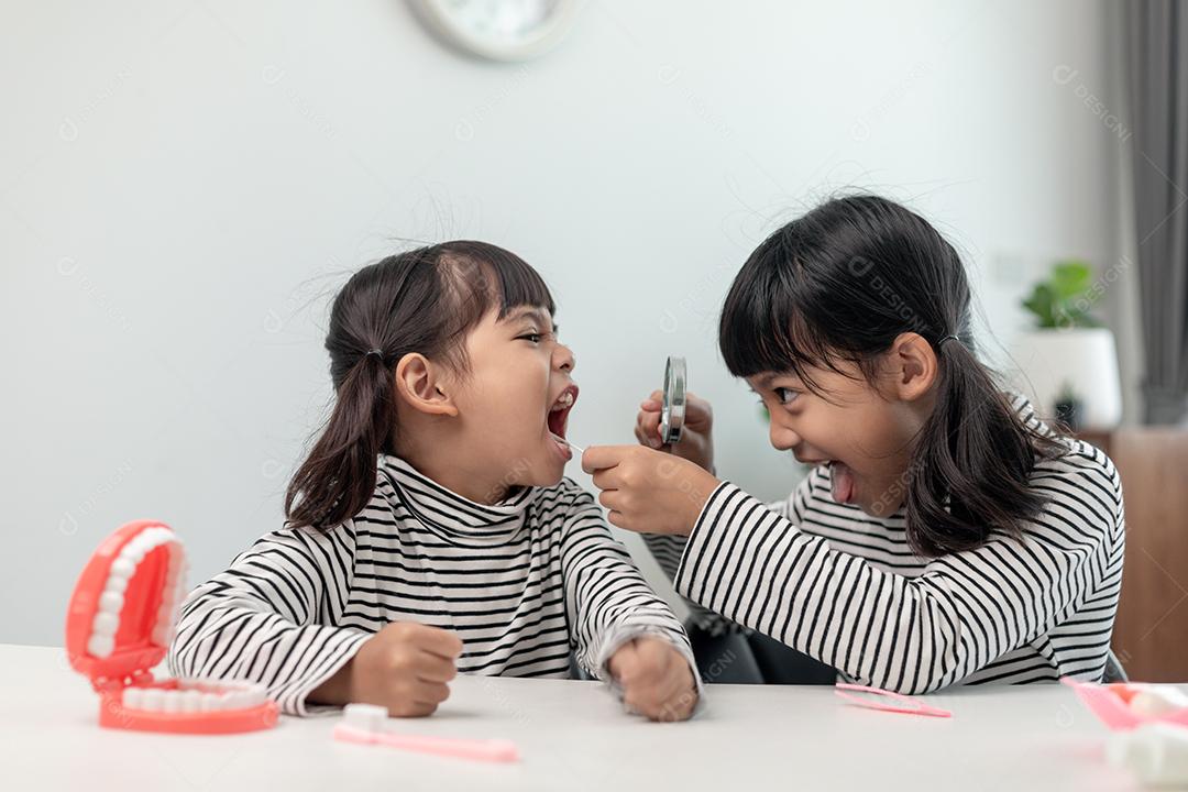 Criança asiática bonita brincando com um conjunto de brinquedos de dentista, criança mostra como limpar e cuidar dos dentes. Odontologia e medicina,