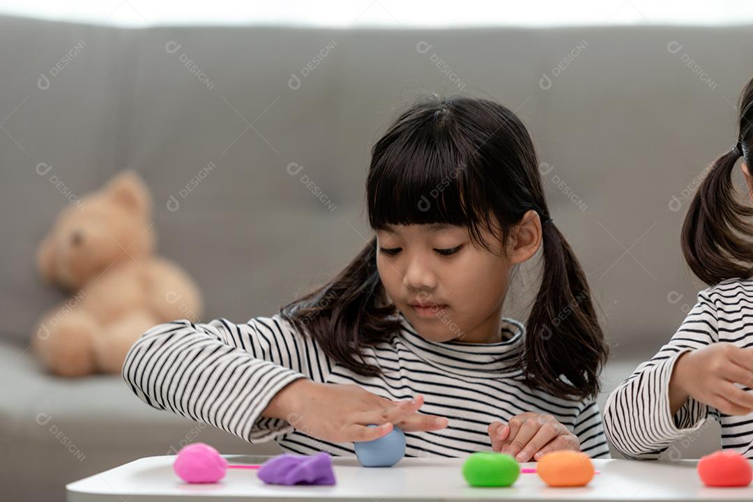 A garotinha está aprendendo a usar massinha colorida em uma sala bem iluminada