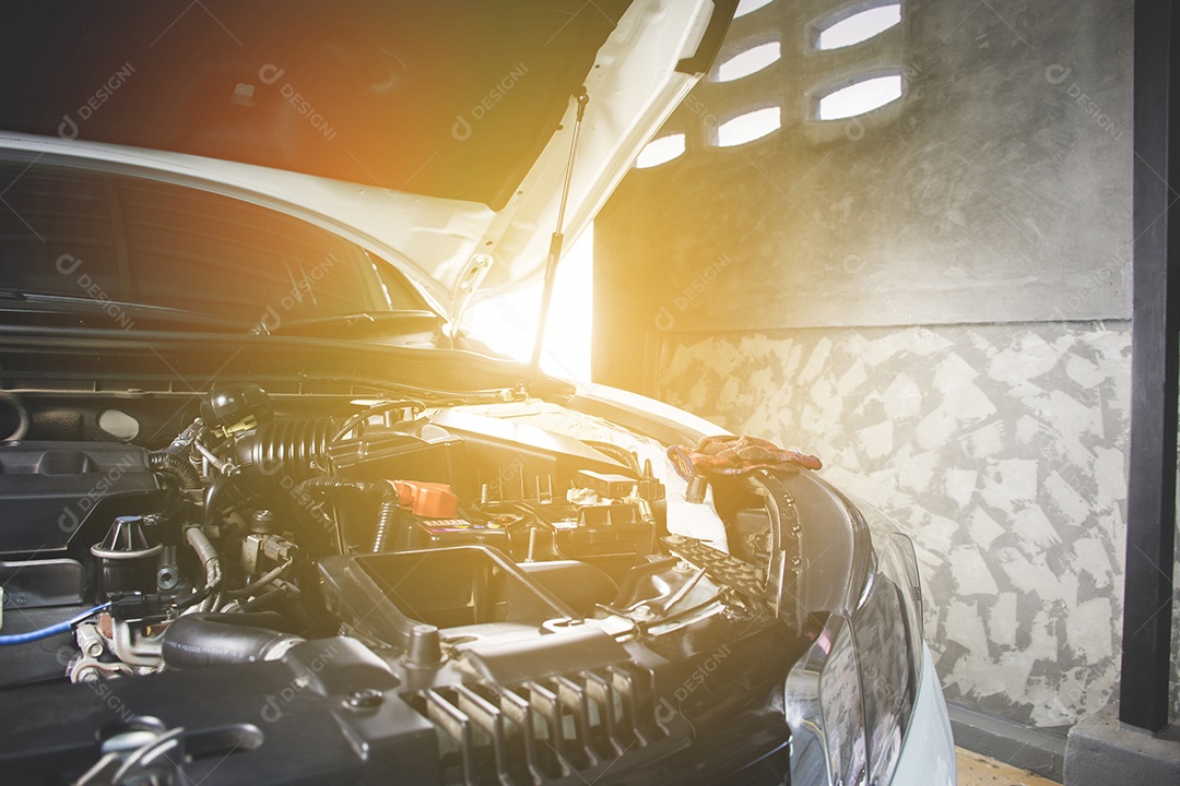 Capô aberto do carro na oficina de reparação de veículos para serviço de manutenção por mecânico, luz solar no fundo.