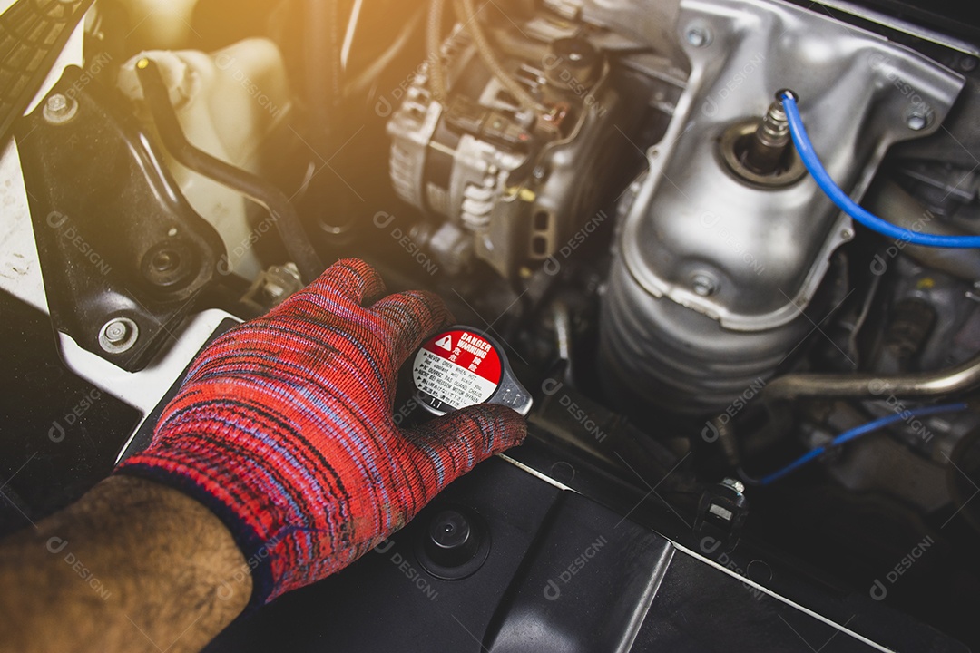 Homem mecânico com luva vermelha está abrindo a tampa do radiador de um carro, conceito de manutenção automotiva.