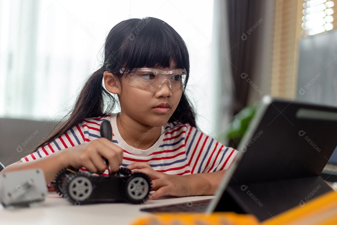 Aluna construindo e programando veículo robô na aula de codificação de computador depois da escola