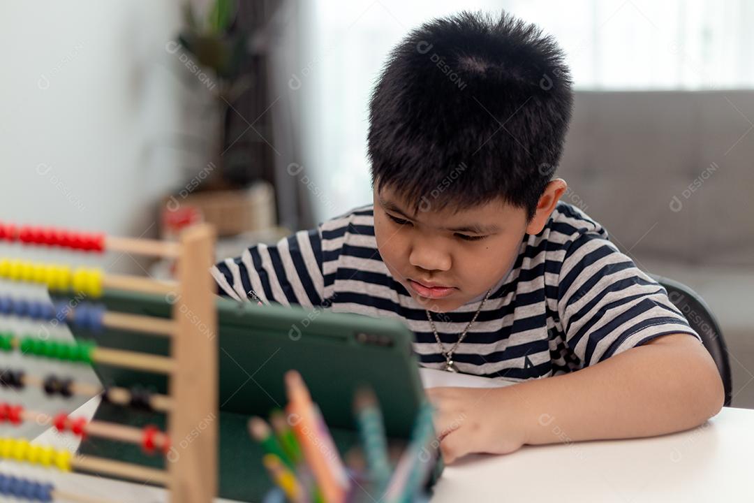 Auto-isolamento infantil usando tablet para sua lição de casa, Criança usando tablet digital pesquisando informações na internet durante o bloqueio covid 19, Educação em casa, Distância social, E-learning educação on-line