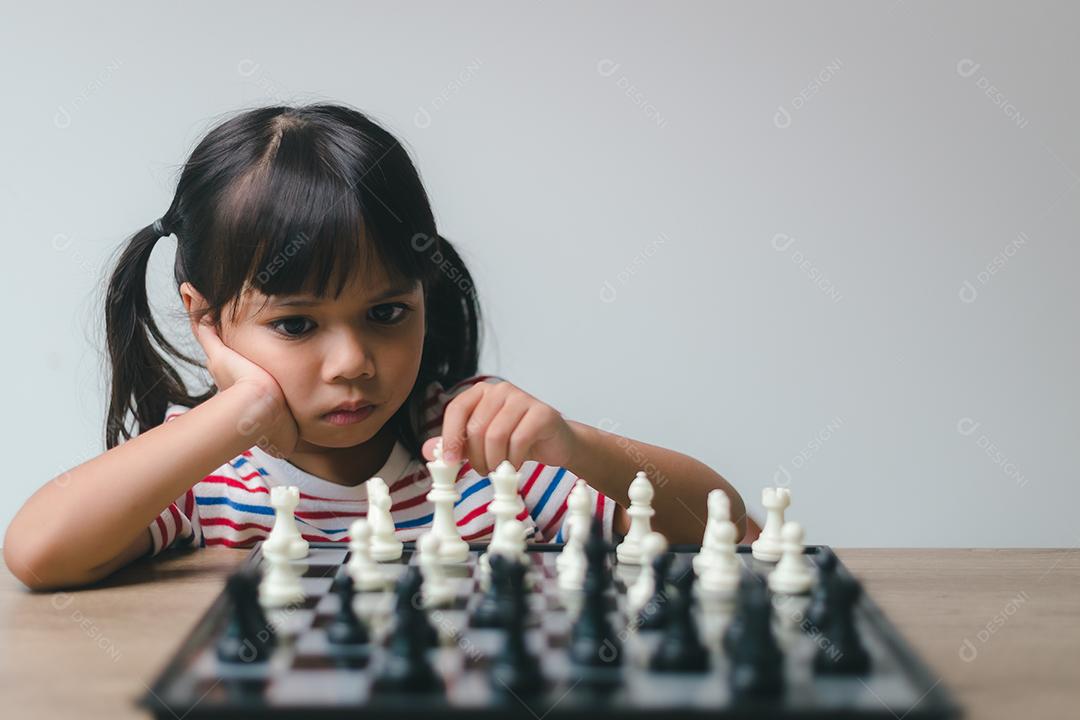 Menina asiática jogando xadrez em casa. um jogo de xadrez