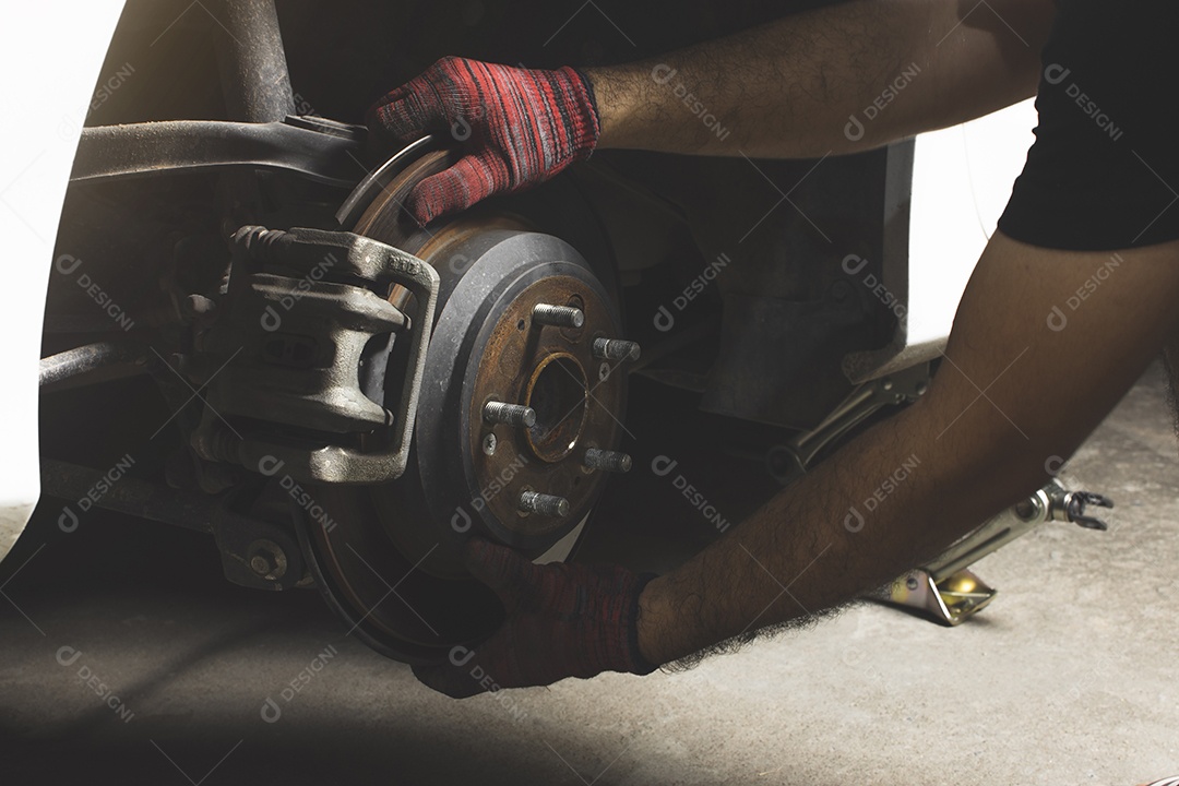 O mecânico de automóveis inspecionou o freio de disco e a pinça no cubo da roda do carro.