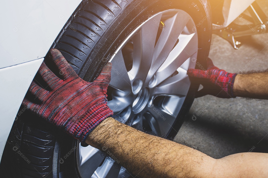 A mão do mecânico segurando a roda de liga leve para trocar a roda de liga no cubo da roda na loja de pneus de carro.