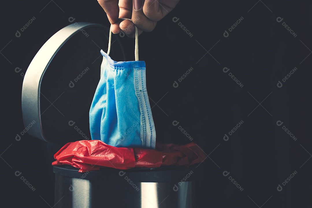 Mão deixar máscara médica descartável na lixeira infectada