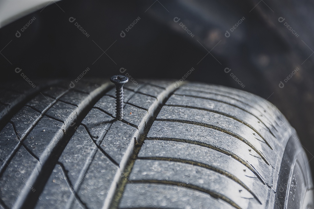 Fechar o parafuso de metal afiado perfurando um pneu de carro