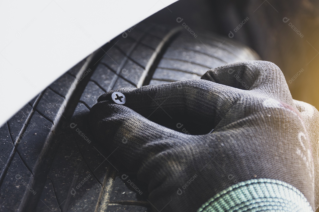 O mecânico puxou o parafuso de metal do pneu do carro