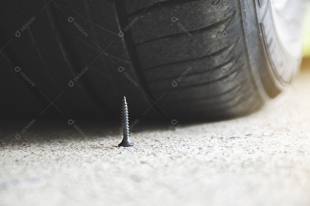 Fechar o parafuso de metal afiado na estrada quase para perfurar um pneu de carro