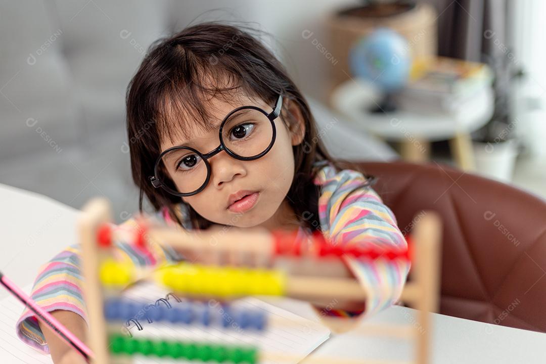 Uma jovem garota asiática bonita está usando o ábaco com contas coloridas