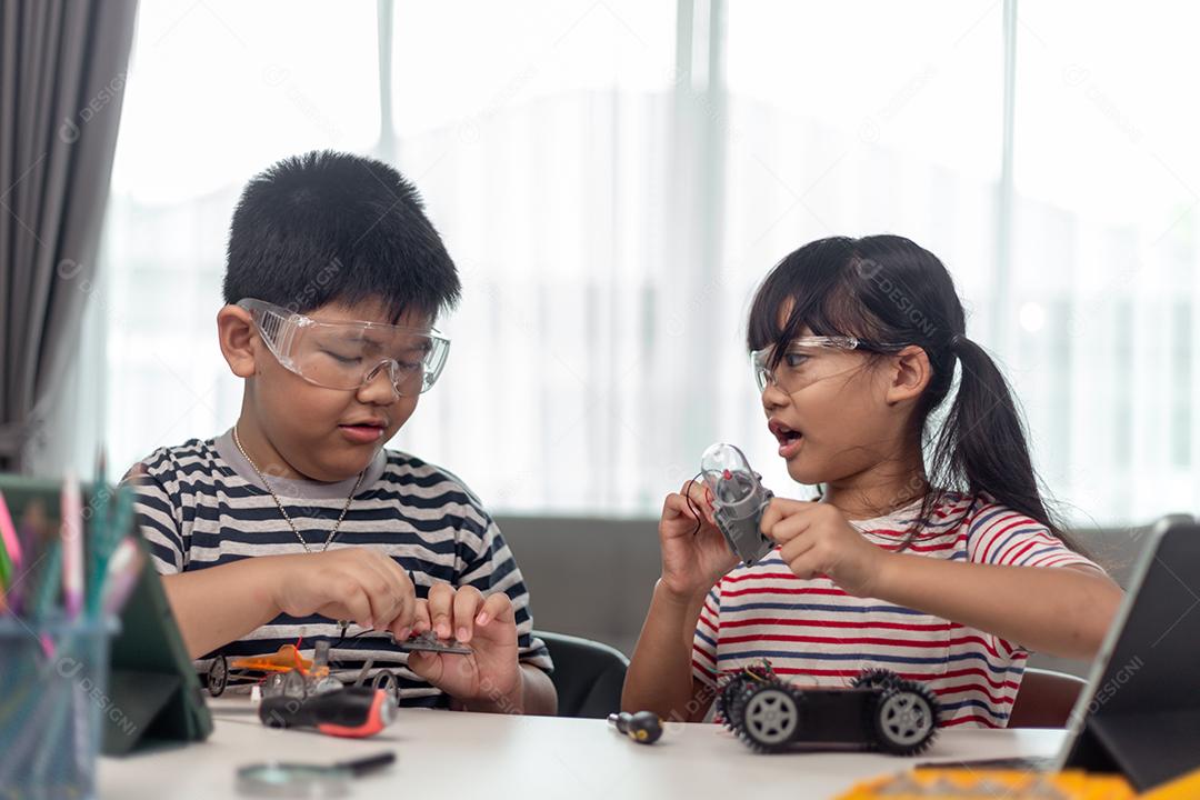 Aluna construindo e programando veículo robô na aula de codificação de computador depois da escola