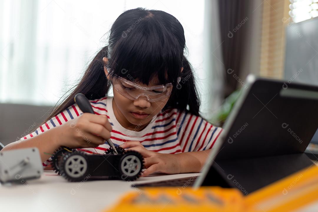 Aluna construindo e programando veículo robô na aula de codificação de computador depois da escola