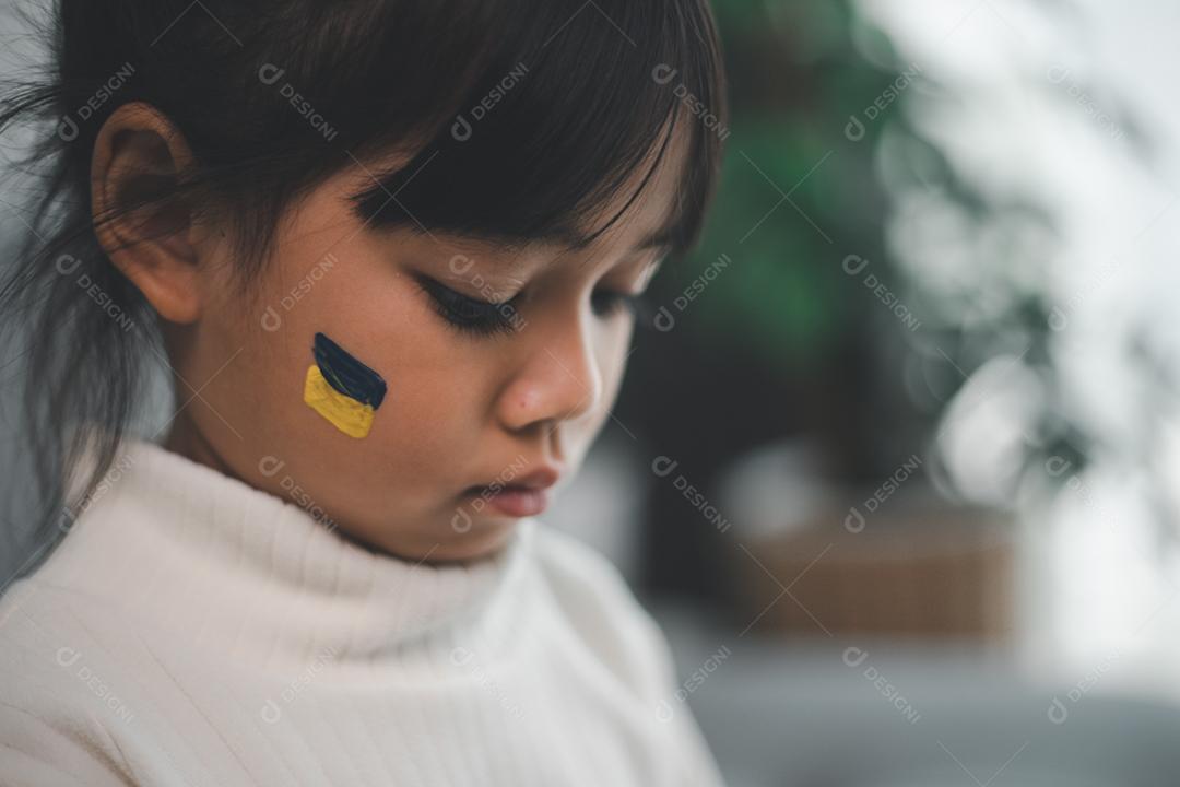 Uma criança com a bandeira da Ucrânia está chorando. Tristeza desejando esperança. As lágrimas das crianças da guerra. Evacuação de civis. Liberdade para a Ucrânia