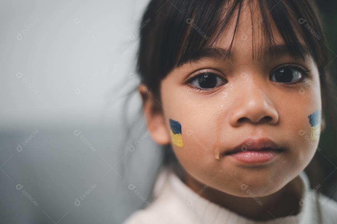 Uma criança com a bandeira da Ucrânia está chorando. Tristeza desejando esperança. As lágrimas das crianças da guerra. Evacuação de civis. Liberdade para a Ucrânia