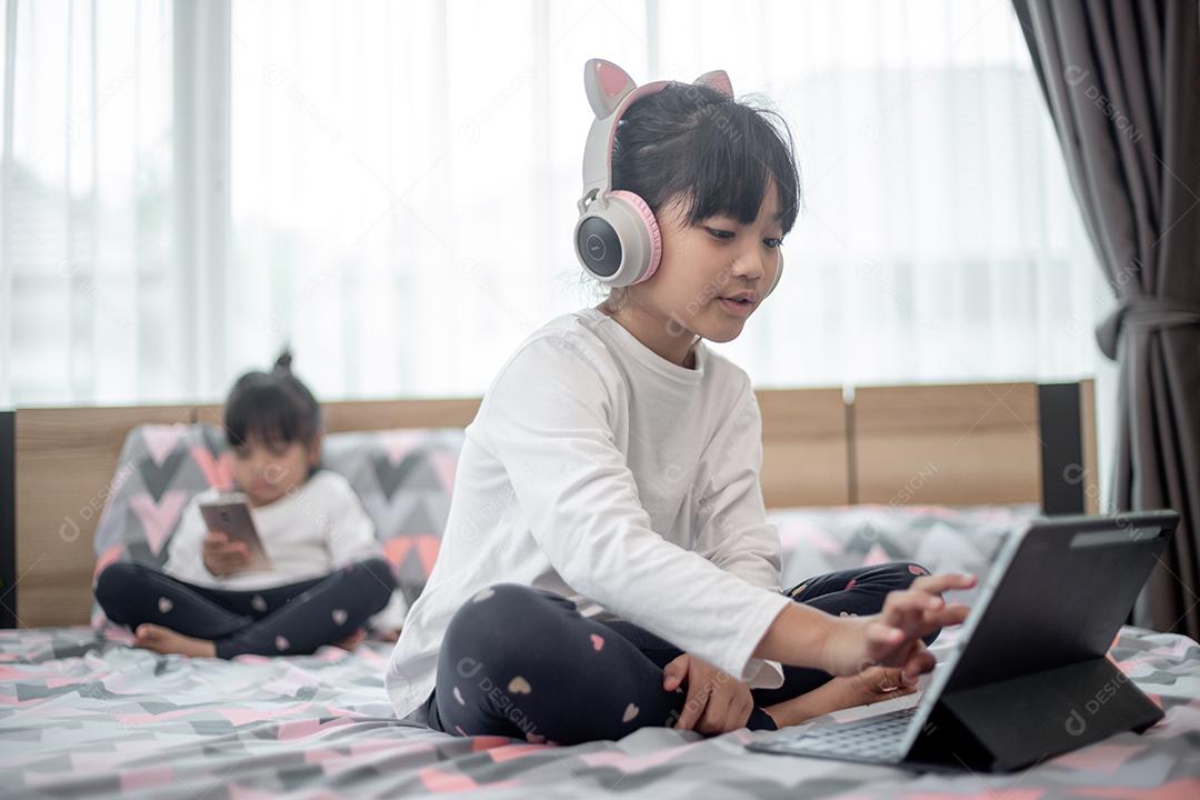 Menina asiática usando um laptop enquanto estava deitado na cama