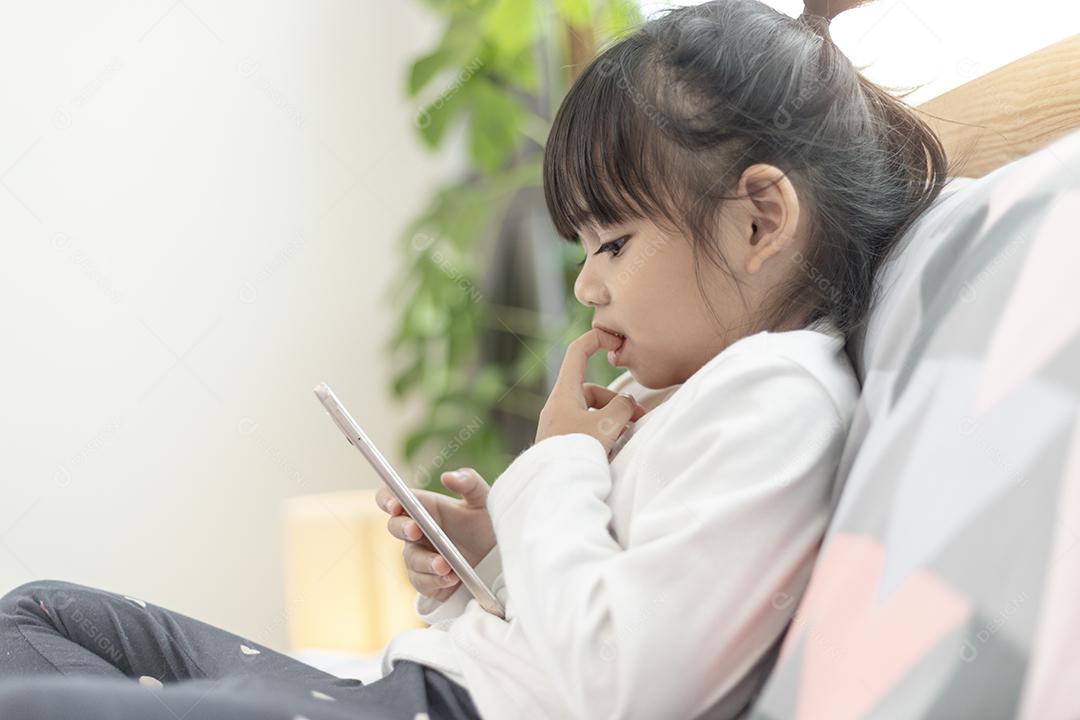 Menina bonitinha assistindo vídeo no smartphone com smiley fa