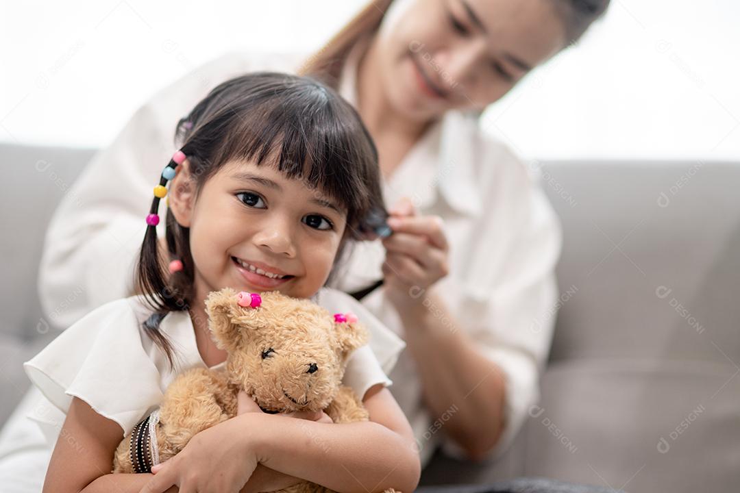 Young Asian mother tying her daughter's hair