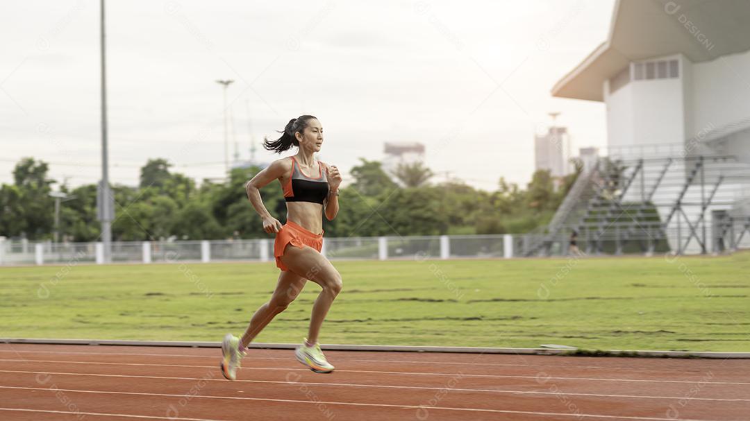 mulher correndo durante a manhã ensolarada na pista do estádio