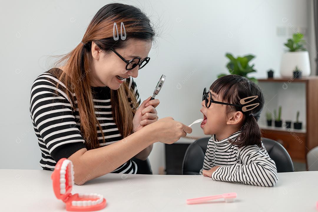 mãe verifica os dentes de leite das filhas. Os dentes crescem em duas fileiras. conceito de odontologia de medicina infantil.