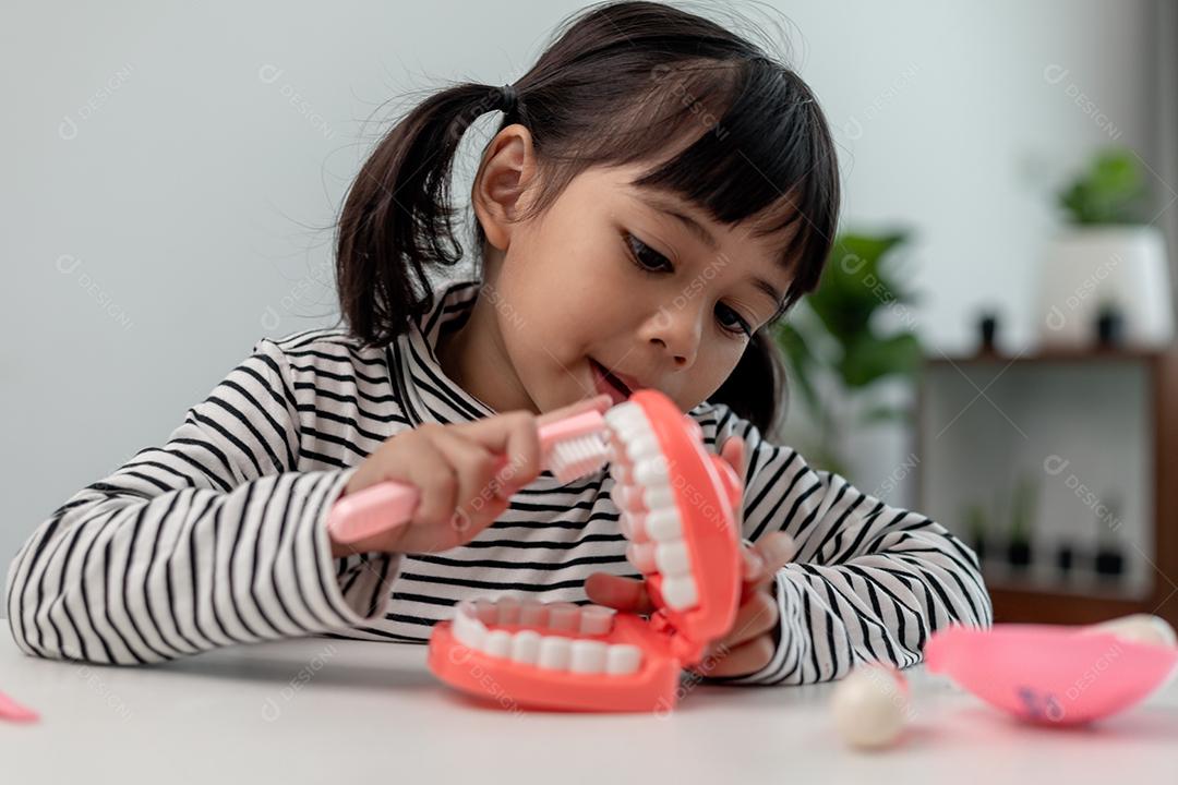 Uma criança pequena brinca com mandíbulas artificiais. Odontologia infantil.