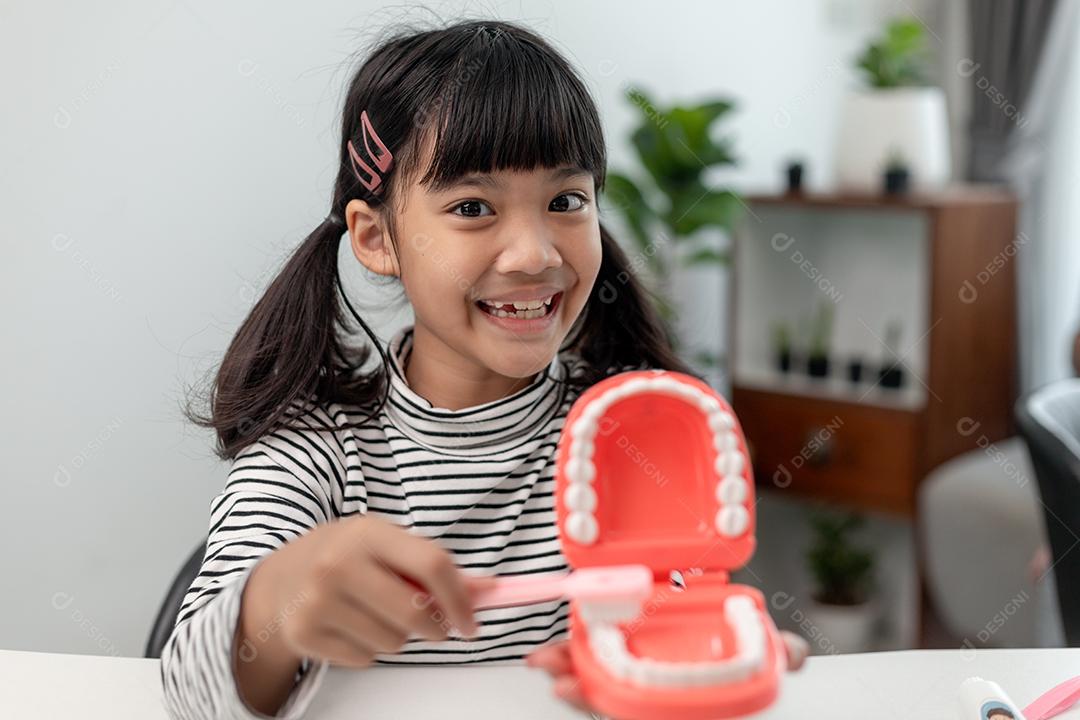 Uma criança pequena brinca com mandíbulas artificiais. Odontologia infantil.