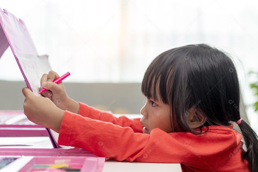 Menina asiática desenhando em casa o desenvolvimento da criatividade.