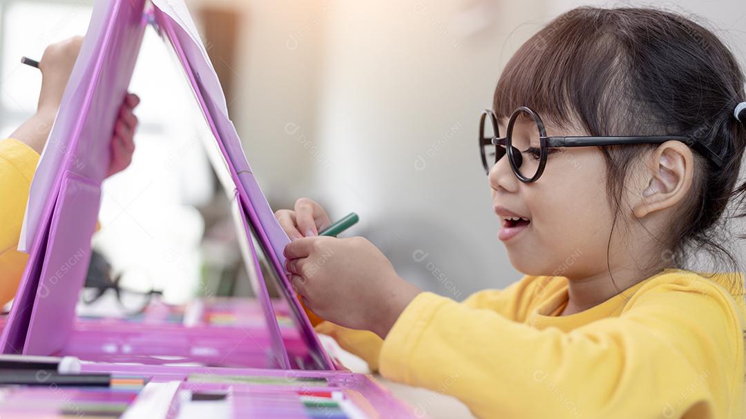 Menina asiática desenhando em casa o desenvolvimento da criatividade.