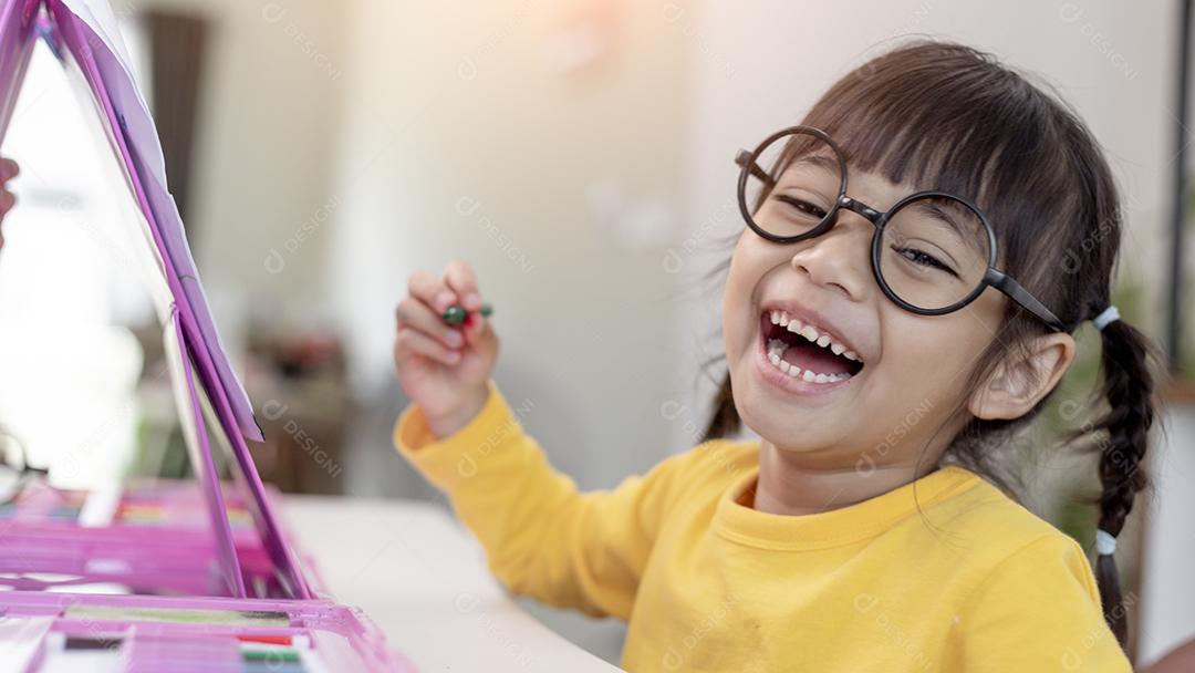 Menina asiática desenhando em casa o desenvolvimento da criatividade.