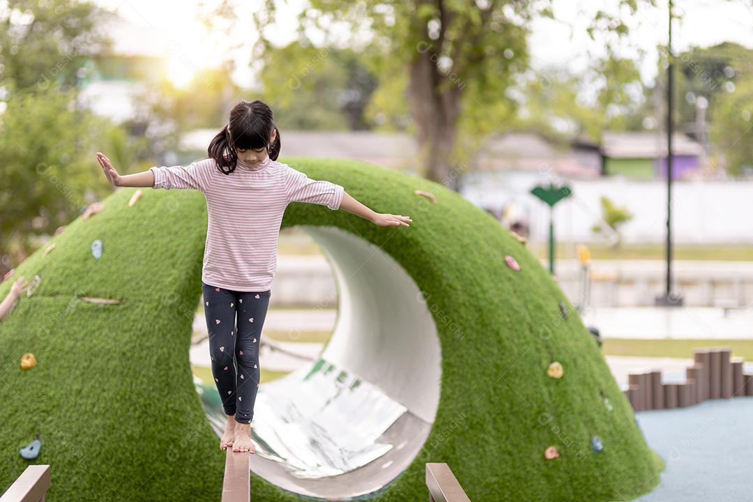 Menina asiática gosta de brincar em um parque infantil, retrato ao ar livre