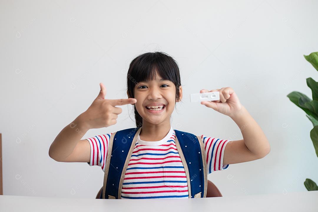 Menina asiática é testada para covid-19 antes da aula.