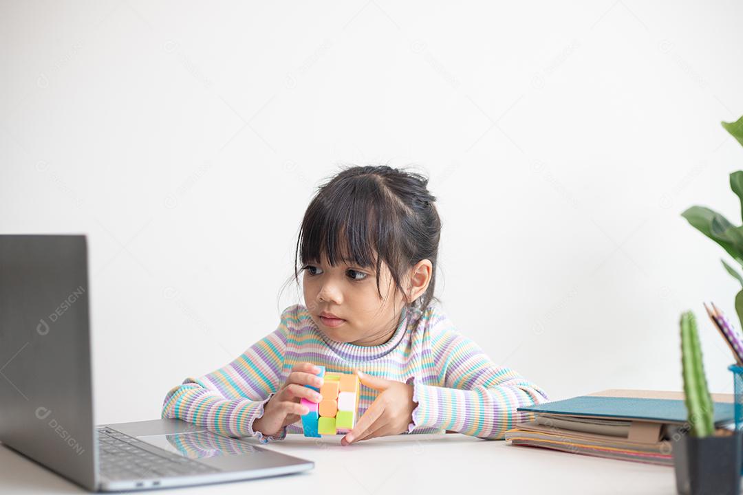NAKHON RATCHASIMA, TAILÂNDIA - 14 DE JULHO DE 2022: Menina asiática bonita segurando o cubo de Rubik em suas mãos. O cubo de Rubik é um jogo que aumenta a inteligência das crianças.