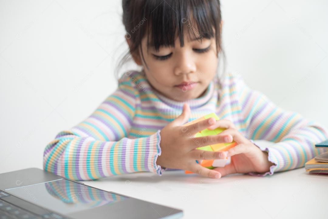 NAKHON RATCHASIMA, TAILÂNDIA - 14 DE JULHO DE 2022: Menina asiática bonita segurando o cubo de Rubik em suas mãos. O cubo de Rubik é um jogo que aumenta a inteligência das crianças.