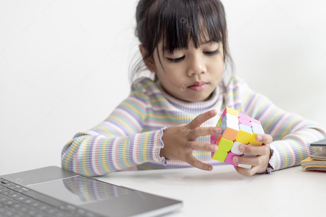 NAKHON RATCHASIMA, TAILÂNDIA - 14 DE JULHO DE 2022: Menina asiática bonita segurando o cubo de Rubik em suas mãos. O cubo de Rubik é um jogo que aumenta a inteligência das crianças.