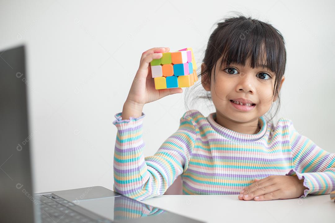 NAKHON RATCHASIMA, TAILÂNDIA - 14 DE JULHO DE 2022: Menina asiática bonita segurando o cubo de Rubik em suas mãos. O cubo de Rubik é um jogo que aumenta a inteligência das crianças.