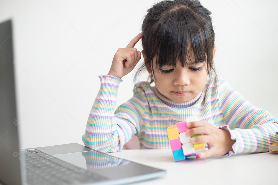 NAKHON RATCHASIMA, TAILÂNDIA - 14 DE JULHO DE 2022: Menina asiática bonita segurando o cubo de Rubik em suas mãos. O cubo de Rubik é um jogo que aumenta a inteligência das crianças.