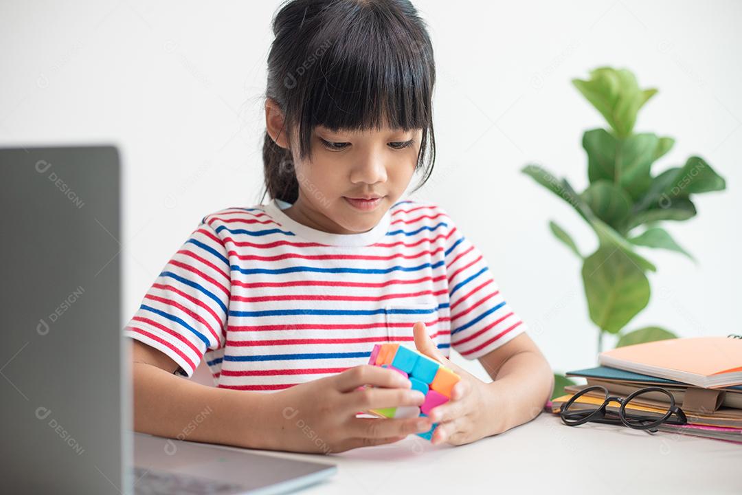 NAKHON RATCHASIMA, TAILÂNDIA - 14 DE JULHO DE 2022: Menina asiática bonita segurando o cubo de Rubik em suas mãos. O cubo de Rubik é um jogo que aumenta a inteligência das crianças.