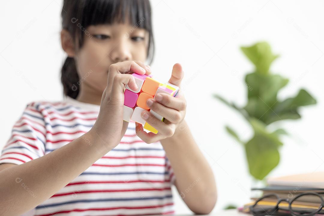 NAKHON RATCHASIMA, TAILÂNDIA - 14 DE JULHO DE 2022: Menina asiática bonita segurando o cubo de Rubik em suas mãos. O cubo de Rubik é um jogo que aumenta a inteligência das crianças.