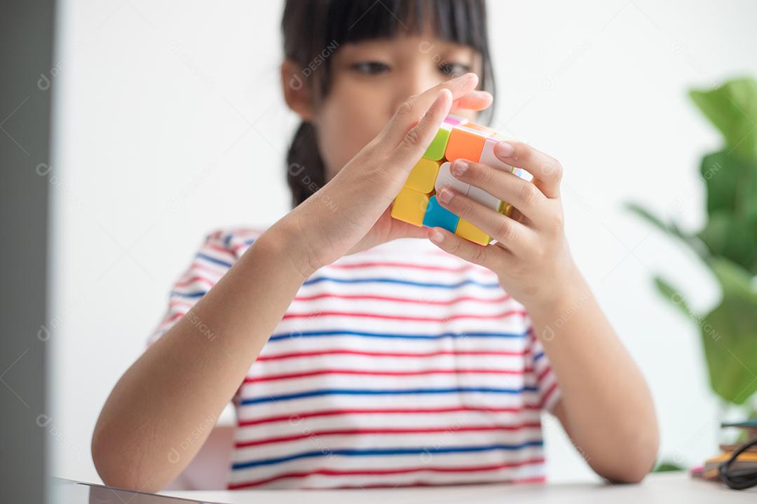 NAKHON RATCHASIMA, TAILÂNDIA - 14 DE JULHO DE 2022: Menina asiática bonita segurando o cubo de Rubik em suas mãos. O cubo de Rubik é um jogo que aumenta a inteligência das crianças.
