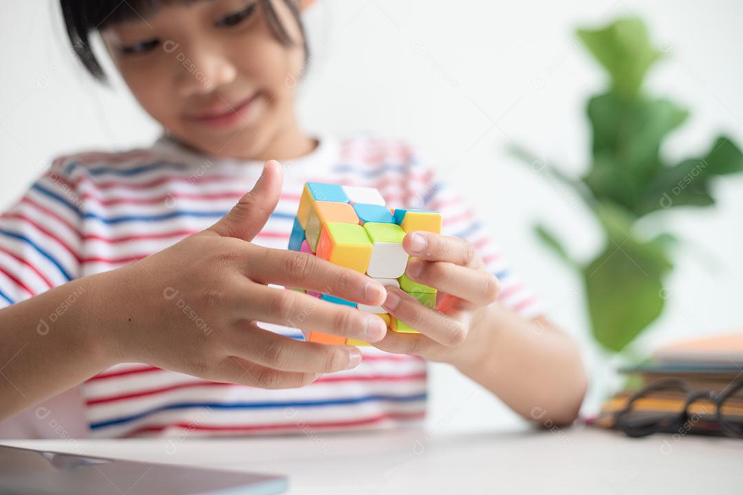 NAKHON RATCHASIMA, TAILÂNDIA - 14 DE JULHO DE 2022: Menina asiática bonita segurando o cubo de Rubik em suas mãos. O cubo de Rubik é um jogo que aumenta a inteligência das crianças.