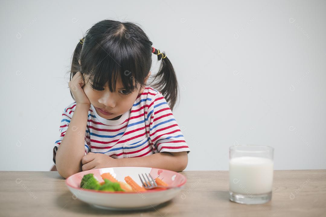 Nutrição & hábitos alimentares saudáveis ​​para o conceito de crianças. As crianças não gostam de comer legumes. Menina bonita se recusa a comer vegetais saudáveis.