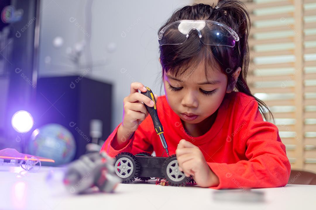 Os alunos da Ásia aprendem em casa na codificação de carros robóticos e cabos de placas eletrônicas em STEM, STEAM, código de computador de tecnologia de ciência de engenharia matemática em robótica para o conceito de crianças.