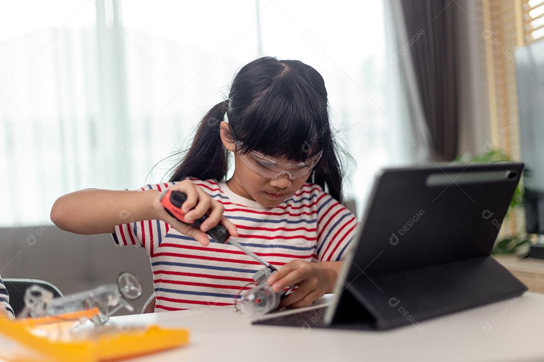 Aluna construindo e programando veículo robô na aula de codificação de computador depois da escola