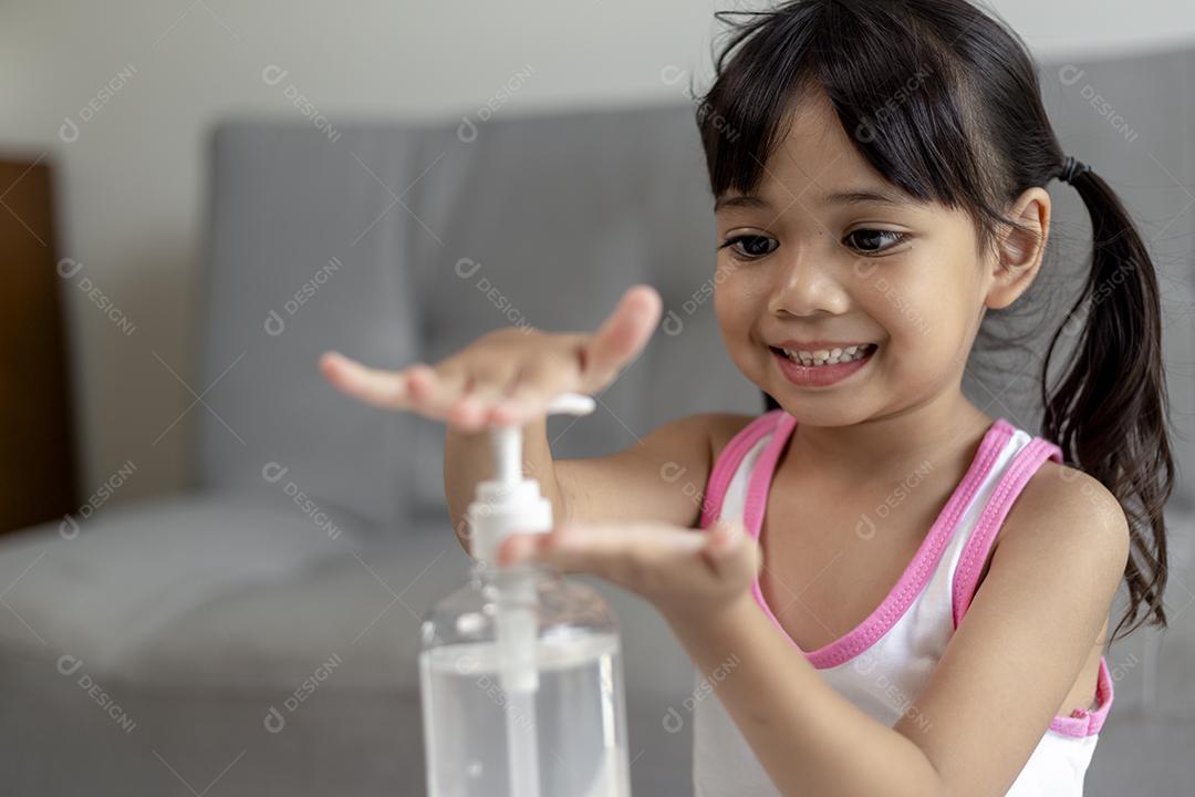 Menina asiática colocou bomba desinfetante de gel de álcool nas mãos para limpar ou lavar as mãos.